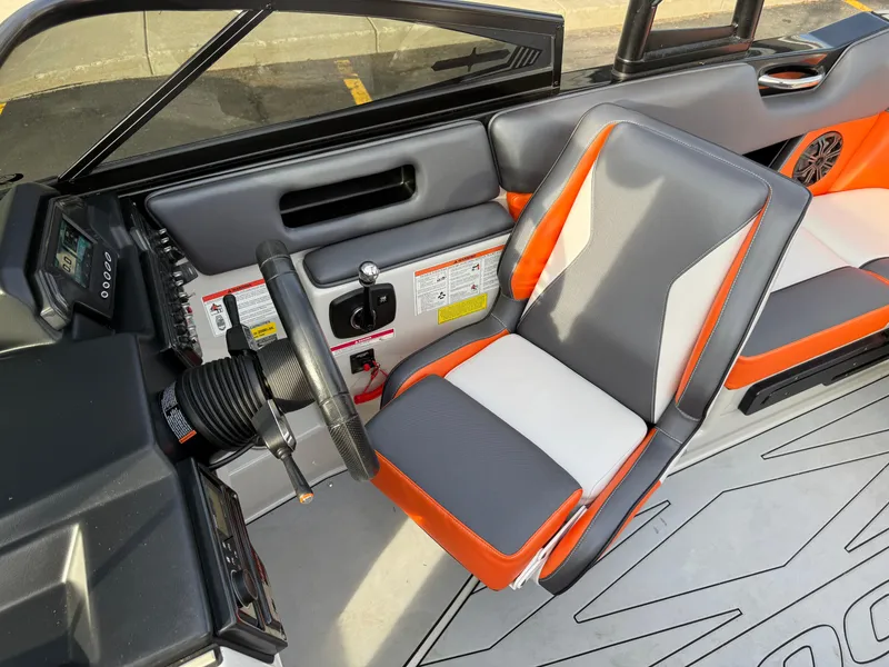 Slide: The Image of 2018 Moomba Helix boat interior with gray and orange seating, steering wheel, and dashboard controls. - 35
