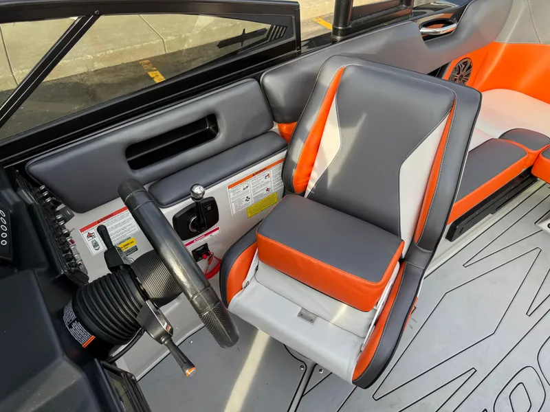 Slide: The Image of 2018 Moomba Helix boat interior with gray and orange seating and steering wheel. - 36