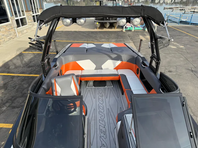 Slide: The Image of 2018 Moomba Helix boat interior with orange and gray seating, docked at a marina. - 37