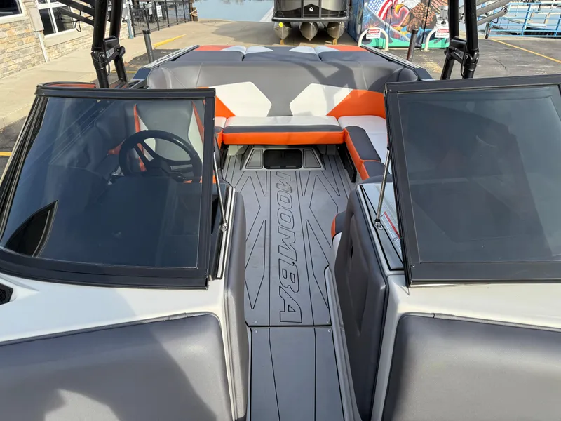 Slide: The Image of 2018 Moomba Helix boat interior with orange and gray seating, open windshield, and steering wheel. - 38
