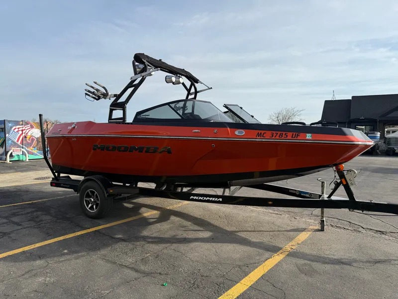 Slide: The Image of 2018 Moomba Helix boat on trailer, vibrant red, parked in a lot. - 5
