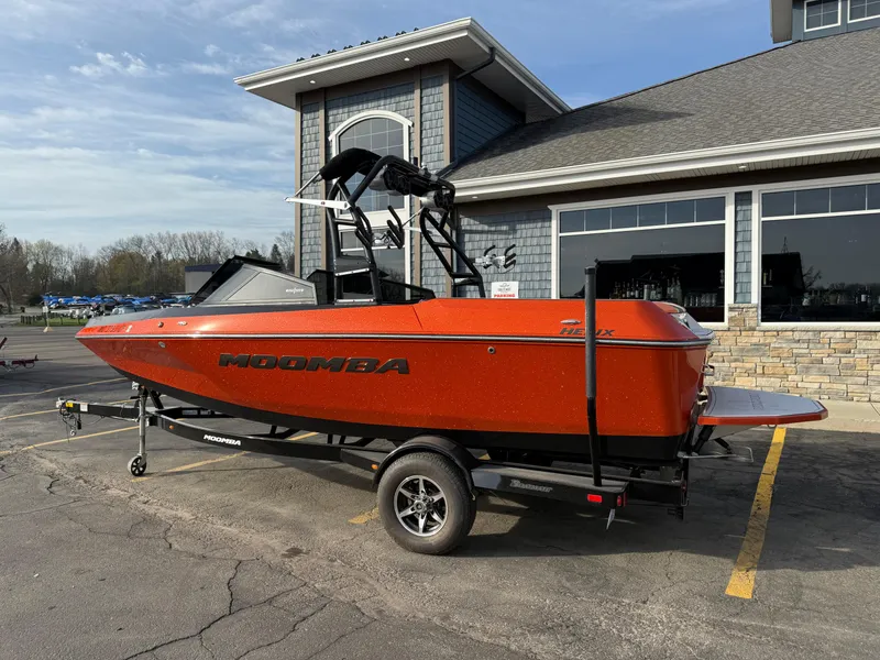 Slide: The Image of 2018 Moomba Helix boat in vibrant orange on a trailer, parked near a building. - 8