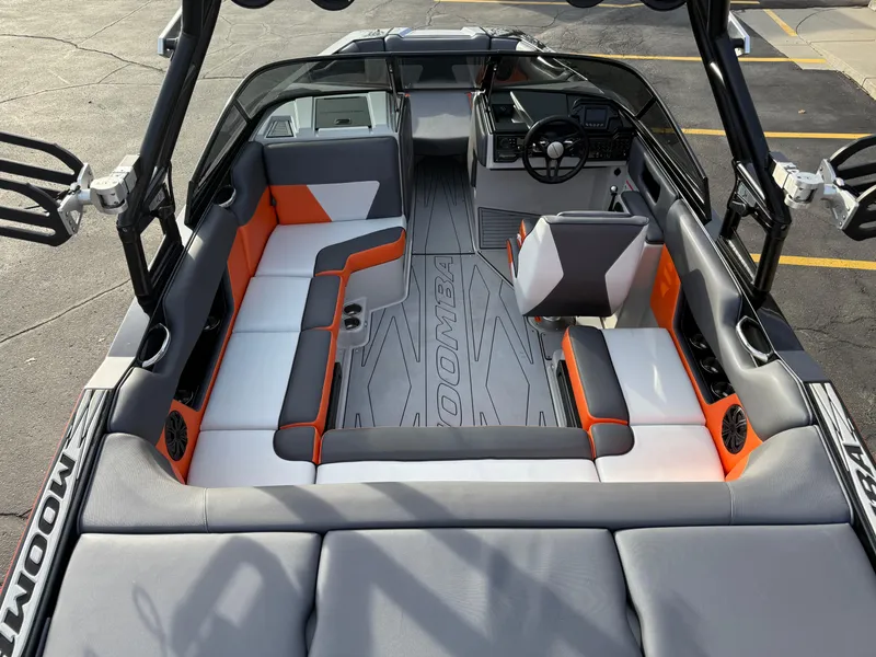 Slide: The Image of 2018 Moomba Helix boat interior with gray and orange seating, spacious layout, and modern dashboard. - 9