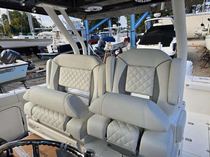Slide: The Image of 2025 Pursuit S 328 boat interior with luxurious quilted seats in a marina setting. - 14