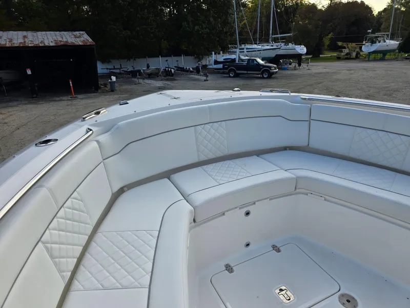 Slide: The Image of 2025 Pursuit S 328 boat with white cushioned seating in a marina setting. - 18