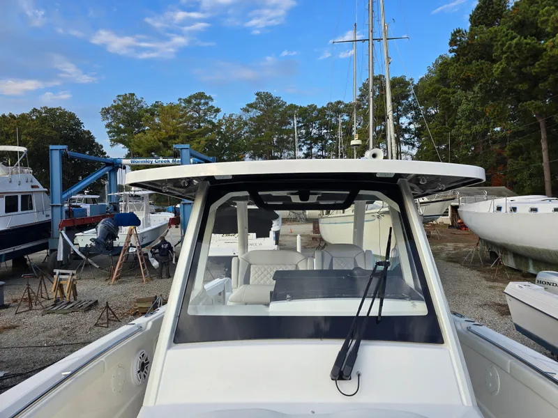 Slide: The Image of 2025 Pursuit S 328 boat in a marina, surrounded by trees and other vessels. - 20