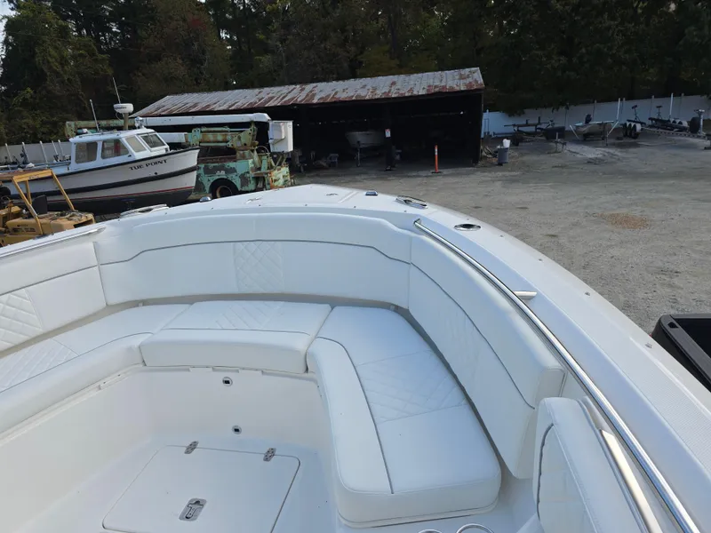 Slide: The Image of 2025 Pursuit S 328 boat with white seating, docked near a rustic shed and other boats. - 21