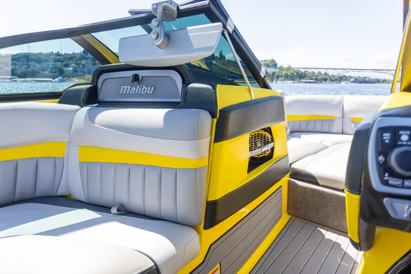 Slide: The Image of 2016 Malibu 24.5 MKZ boat interior with yellow and gray seating, on a sunny day. - 11