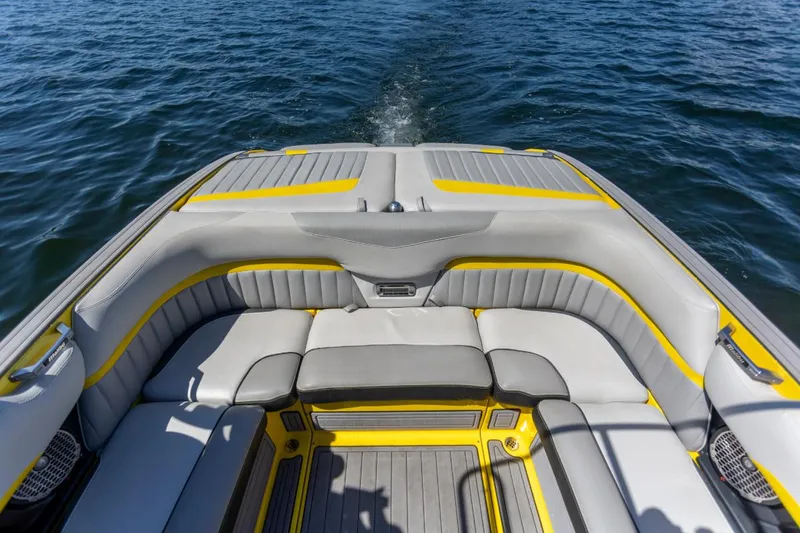 Slide: The Image of 2016 Malibu 24.5 MKZ boat interior with gray and yellow seating on water. - 21