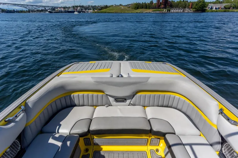 Slide: The Image of 2016 Malibu 24.5 MKZ boat interior with gray and yellow seating on a sunny day. - 22