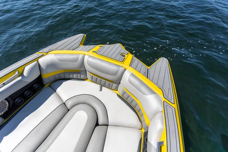 Slide: The Image of 2016 Malibu 24.5 MKZ boat interior with yellow and gray seating on water. - 24
