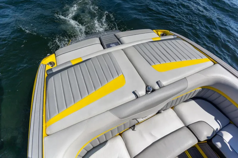 Slide: The Image of 2016 Malibu 24.5 MKZ boat with yellow and gray seating on water. - 25
