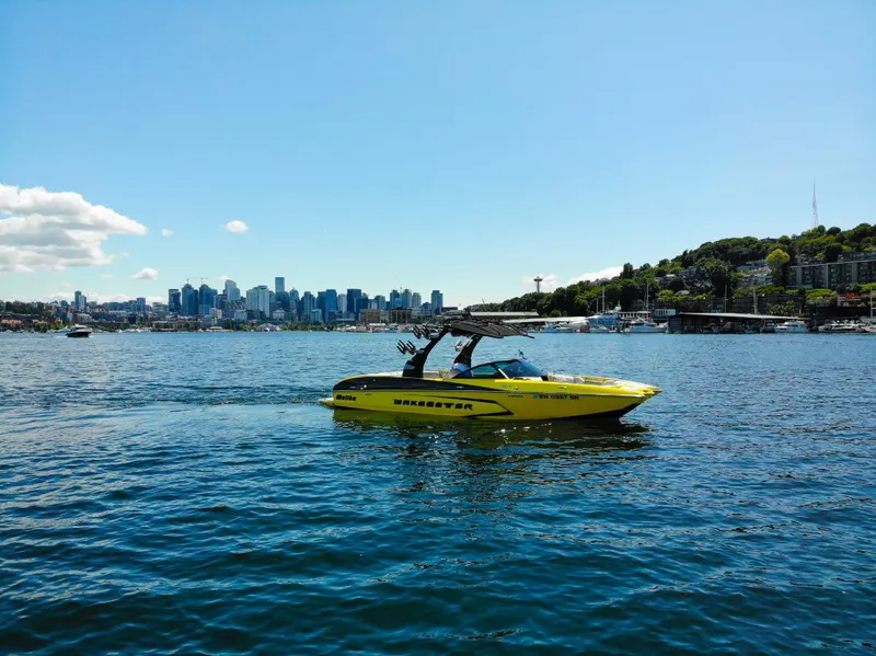 Slide: The Image of Yellow 2016 Malibu 24.5 MKZ boat on water with city skyline in background. - 39