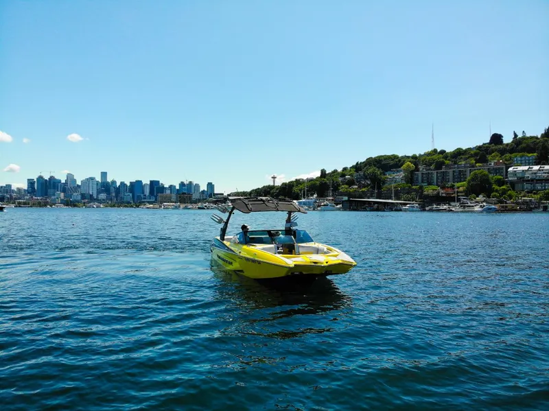 Slide: The Image of Yellow 2016 Malibu 24.5 MKZ boat on water with city skyline in background. - 40