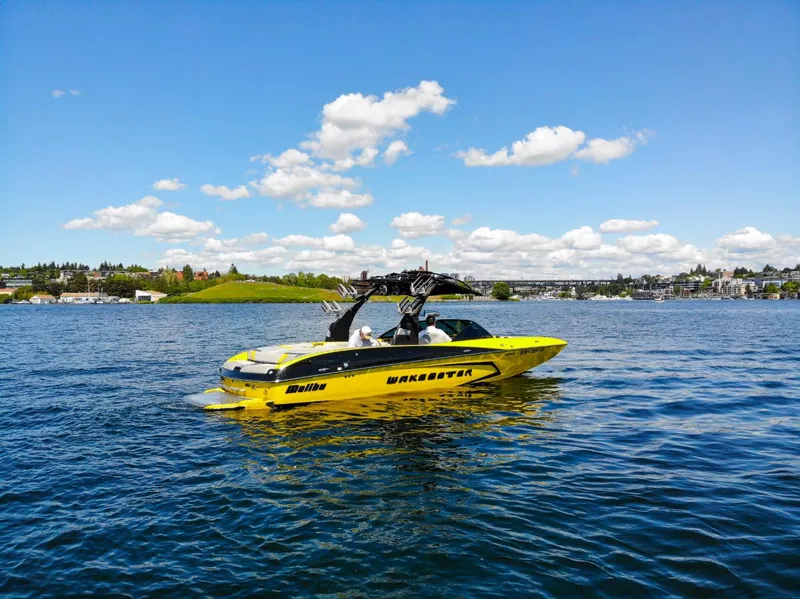 Slide: The Image of Yellow 2016 Malibu 24.5 MKZ boat cruising on a sunny lake. - 42
