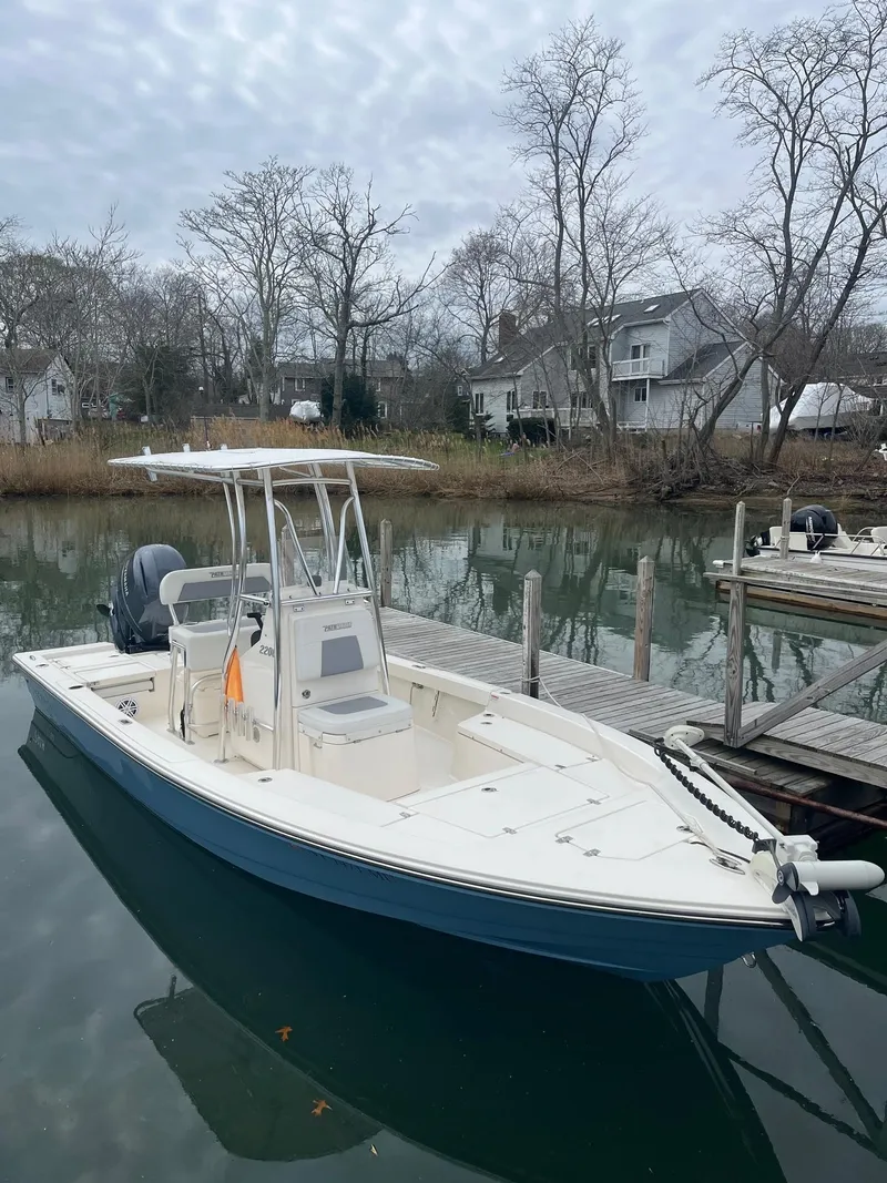 The Image of 2023 Pathfinder 2200 TRS boat docked on a calm, tree-lined waterway. - 1