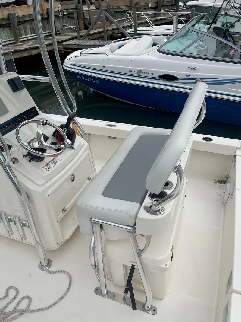 Slide: The Image of 2023 Pathfinder 2200 TRS boat interior with steering console and seating at a marina. - 4
