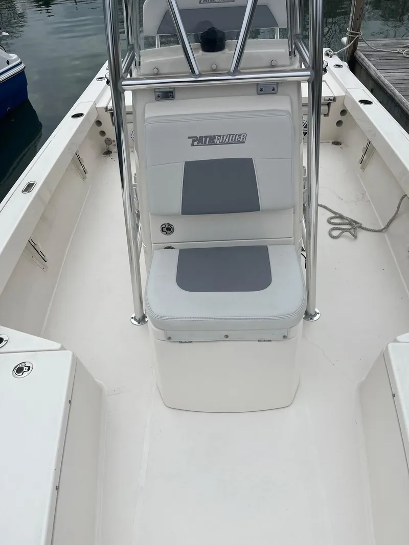 Slide: The Image of 2023 Pathfinder 2200 TRS boat interior with seating and console, docked by the water. - 8