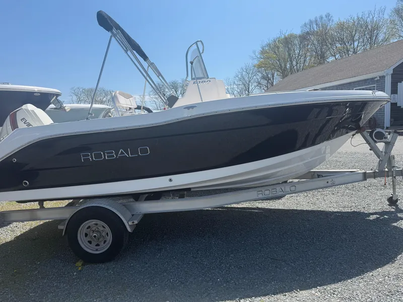 Slide: The Image of 2018 Robalo R180 Center Console boat on trailer, black hull, sunny day. - 0