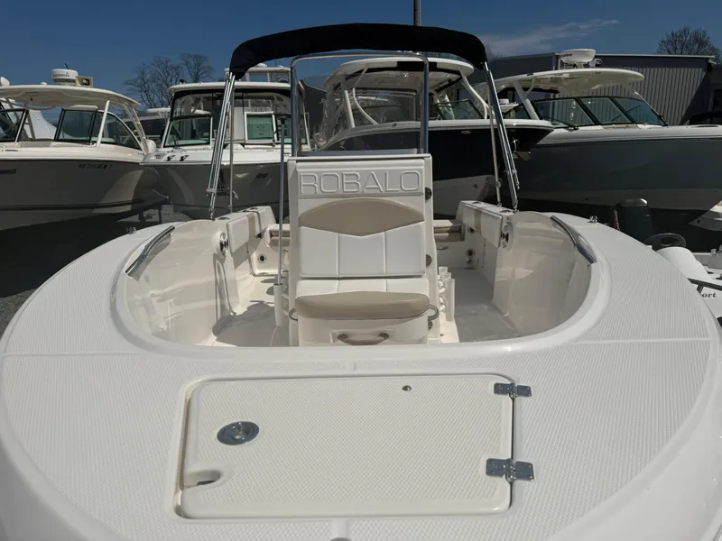 Slide: The Image of 2018 Robalo R180 Center Console boat with white seating and console, docked among other boats. - 12