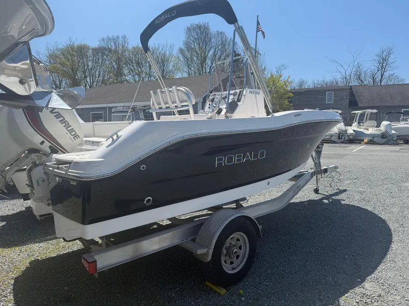 Slide: The Image of 2018 Robalo R180 Center Console boat on trailer, parked outdoors. - 2