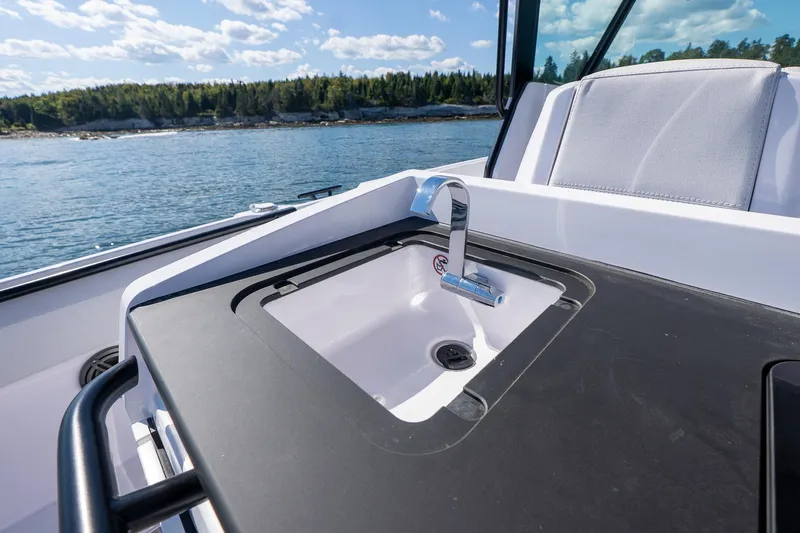 Slide: The Image of 2025 Axopar CCX Center Console boat on calm water under blue sky. - 11