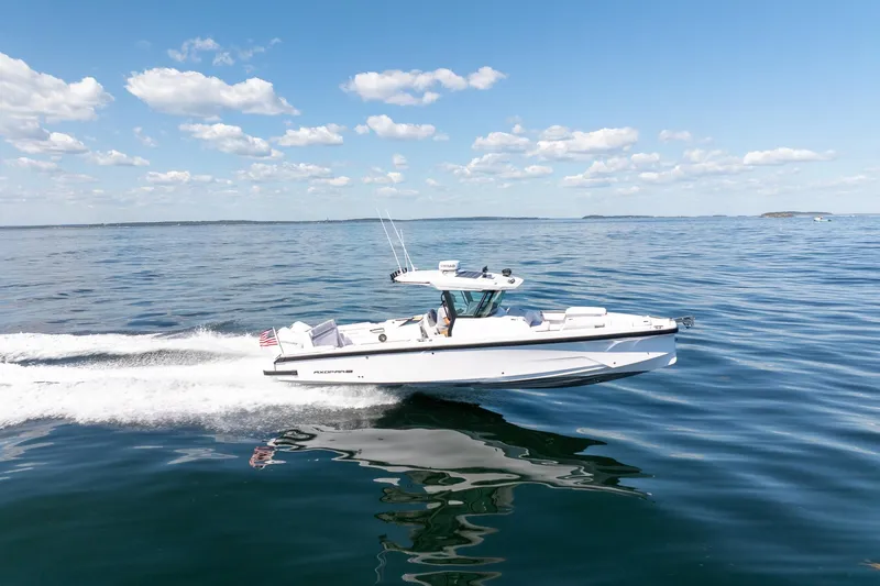 Slide: The Image of 2025 Axopar CCX Center Console boat cruising on open water under a clear blue sky. - 2