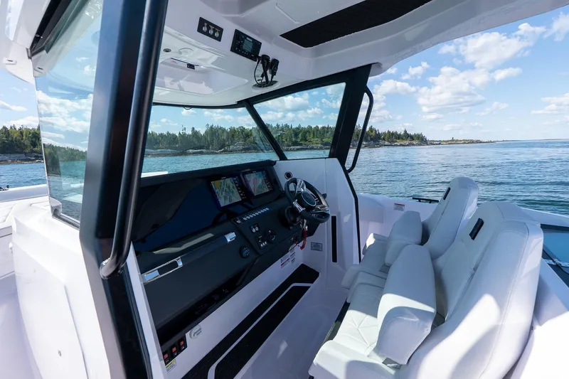 Slide: The Image of 2025 Axopar CCX Center Console boat interior with modern navigation system on a scenic waterway. - 23