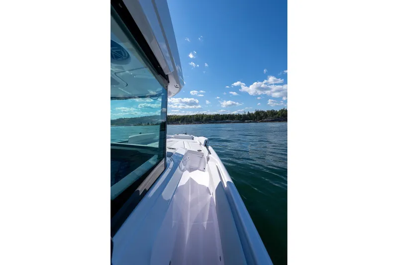 Slide: The Image of 2025 Axopar CCX Center Console boat on serene water with clear sky. - 37
