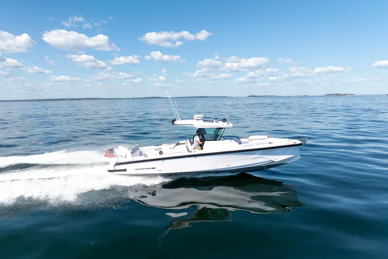 Slide: The Image of 2025 Axopar CCX Center Console boat cruising on open water under clear blue sky. - 4