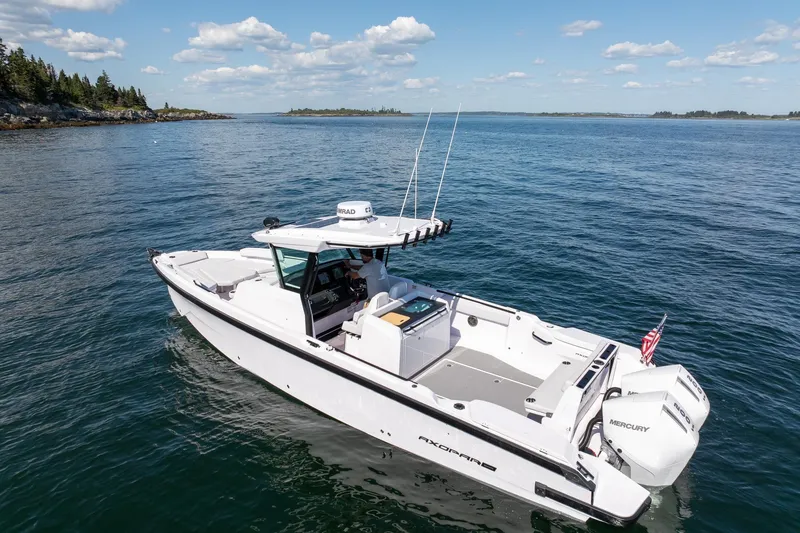 Slide: The Image of 2025 Axopar CCX Center Console boat cruising on open water under a clear blue sky. - 5