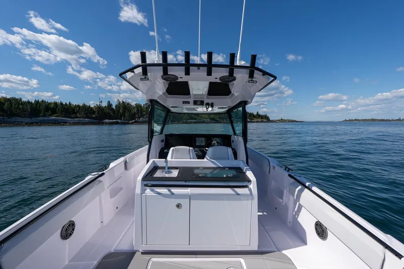 Slide: The Image of 2025 Axopar CCX Center Console boat cruising on open water under a clear blue sky. - 9