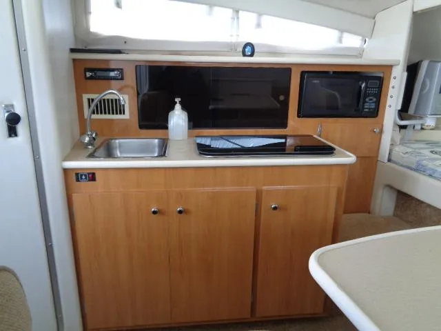Slide: The Image of 2002 Bayliner 2855 Ciera boat interior kitchen with sink, stove, and microwave. - 17