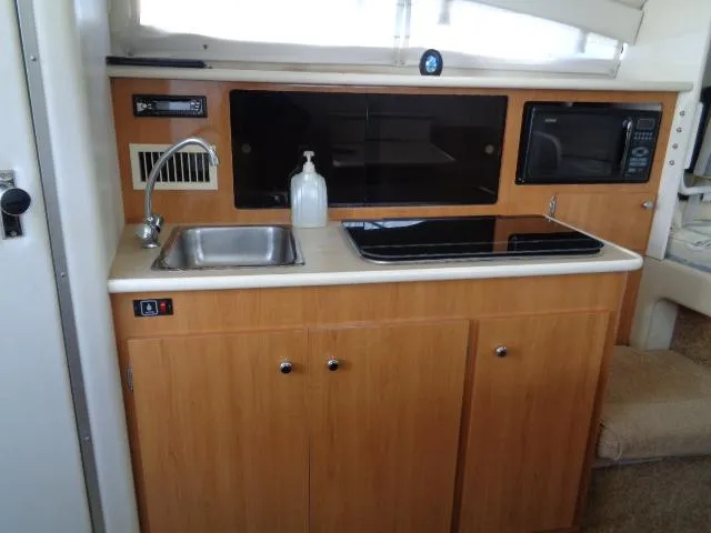 Slide: The Image of 2002 Bayliner 2855 Ciera boat kitchen with sink, stove, and microwave. - 18