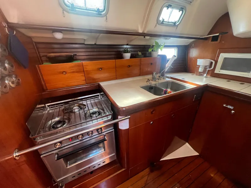 Slide: The Image of Interior of 1994 Beneteau Oceanis 440 yacht kitchen with stove, sink, and wooden cabinetry. - 13