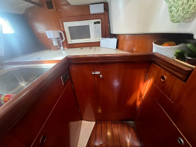 Slide: The Image of Beneteau Oceanis 440 yacht kitchen with wooden cabinetry, sink, and microwave, 1994 model. - 15
