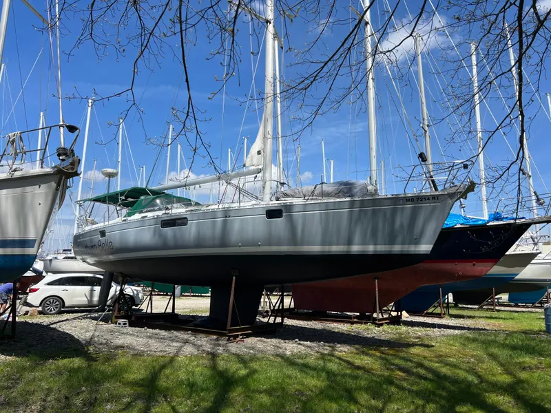 Slide: The Image of 1994 Beneteau Oceanis 440 sailboat on land, surrounded by other boats, under a clear blue sky. - 8