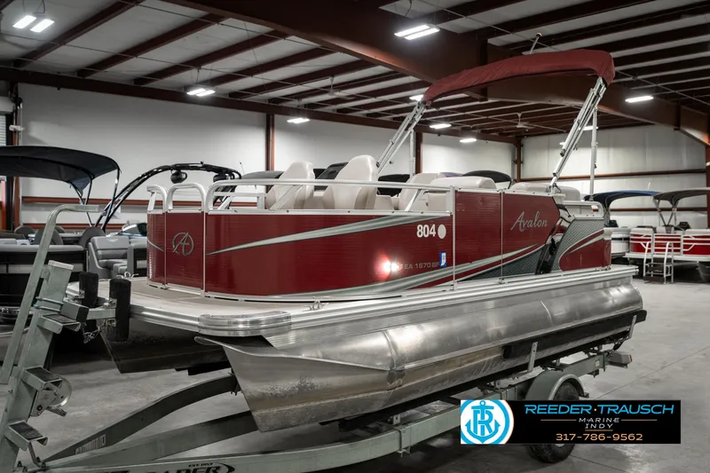Slide: The Image of 2019 Avalon Eagle pontoon boat in a showroom, featuring a red exterior and white seating. - 2