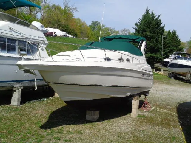 Slide: The Image of 2001 Regal Commodore 2760 boat on dry dock with green canopy, surrounded by trees. - 0