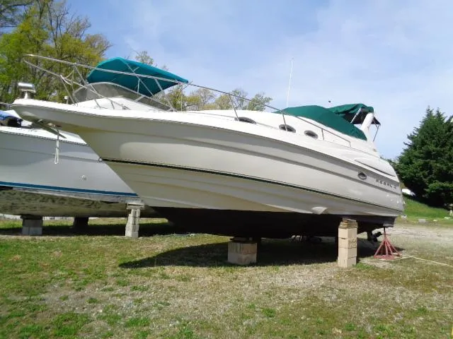 Slide: The Image of 2001 Regal Commodore 2760 boat on dry land, white hull, green canopy, parked on blocks. - 4