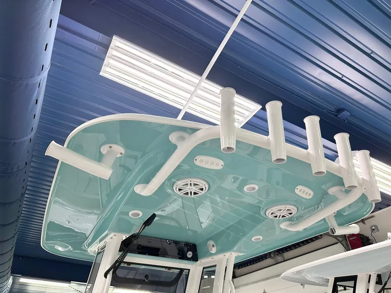 Slide: The Image of 2025 Sportsman Open 232 Center Console boat with rod holders and speakers under blue canopy. - 5