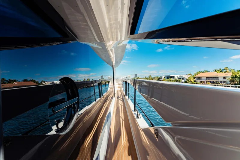 Slide: The Image of 2023 Ferretti Yachts 860, sleek deck view with reflections, clear blue sky, and waterfront homes. - 14