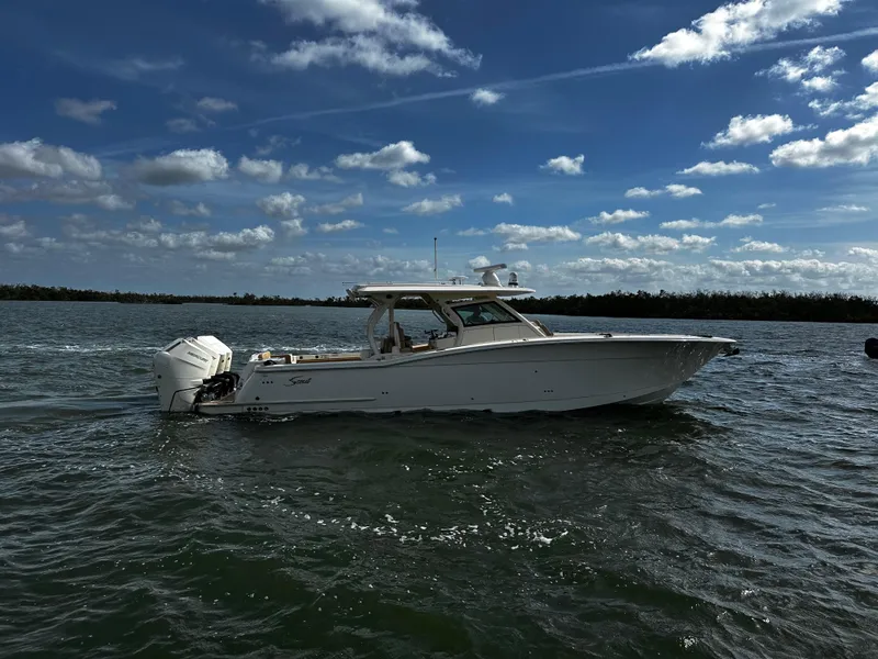 Slide: The Image of 2025 Scout 400 LXF boat cruising on a sunny day with blue skies and clouds. - 1