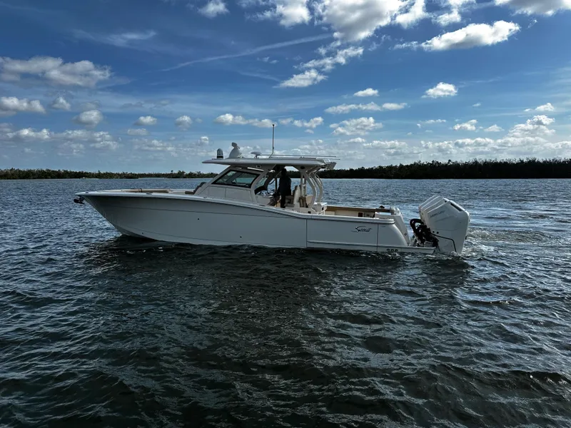 Slide: The Image of 2025 Scout 400 LXF boat on water under blue sky with clouds. - 10