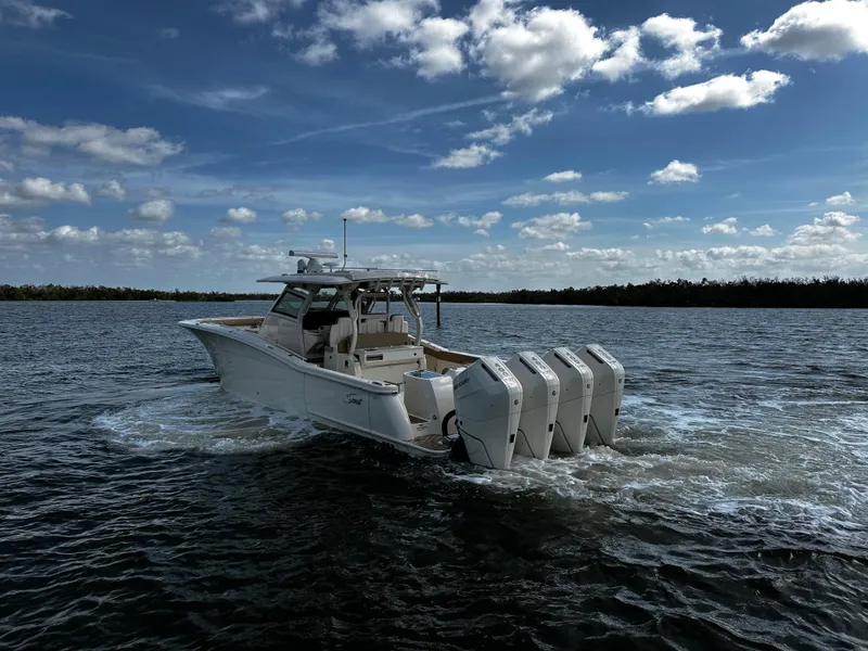 Slide: The Image of 2025 Scout 400 LXF boat cruising on open water under a partly cloudy sky. - 11