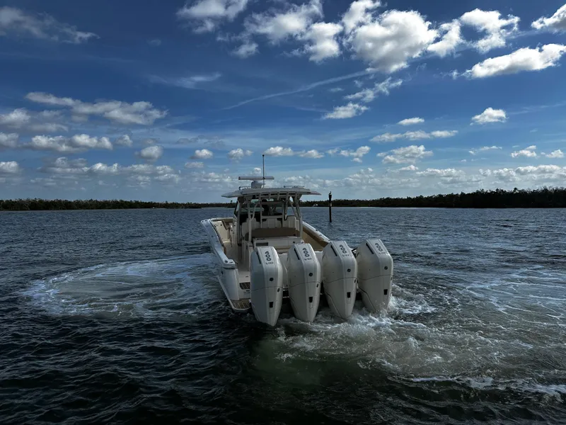 Slide: The Image of 2025 Scout 400 LXF boat with four engines cruising on open water under a cloudy sky. - 12