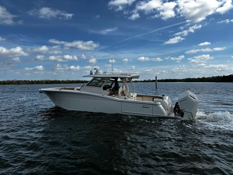 Slide: The Image of 2025 Scout 400 LXF boat cruising on open water under a partly cloudy sky. - 13