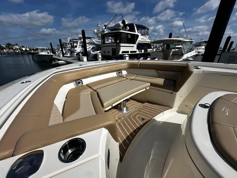 Slide: The Image of 2025 Scout 400 LXF boat interior with tan seating, docked at marina under blue sky. - 25