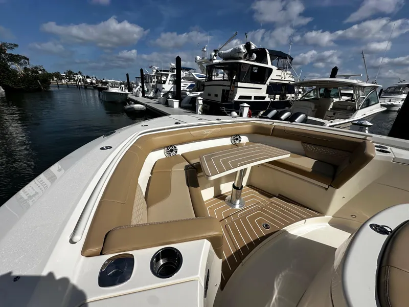 Slide: The Image of 2025 Scout 400 LXF boat interior with seating and table, docked at marina under blue sky. - 26
