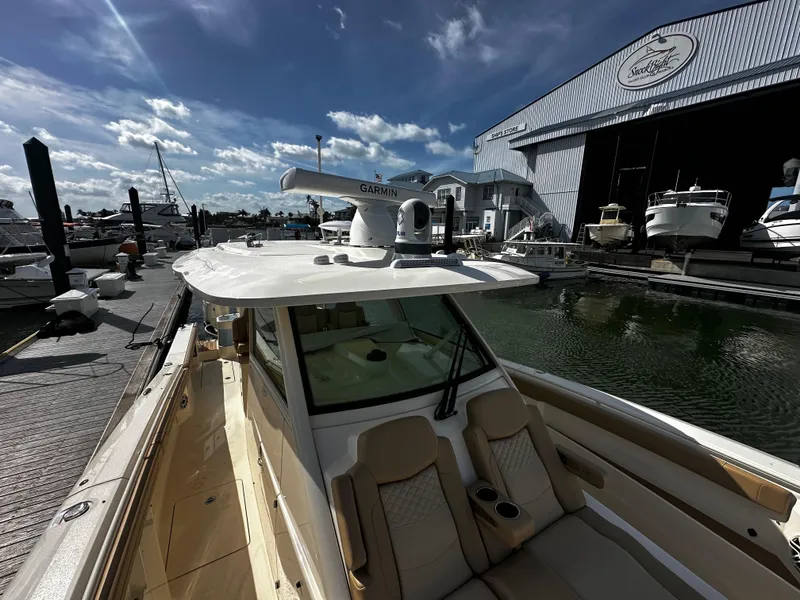 Slide: The Image of 2025 Scout 400 LXF boat docked near marina with clear sky and water. - 28